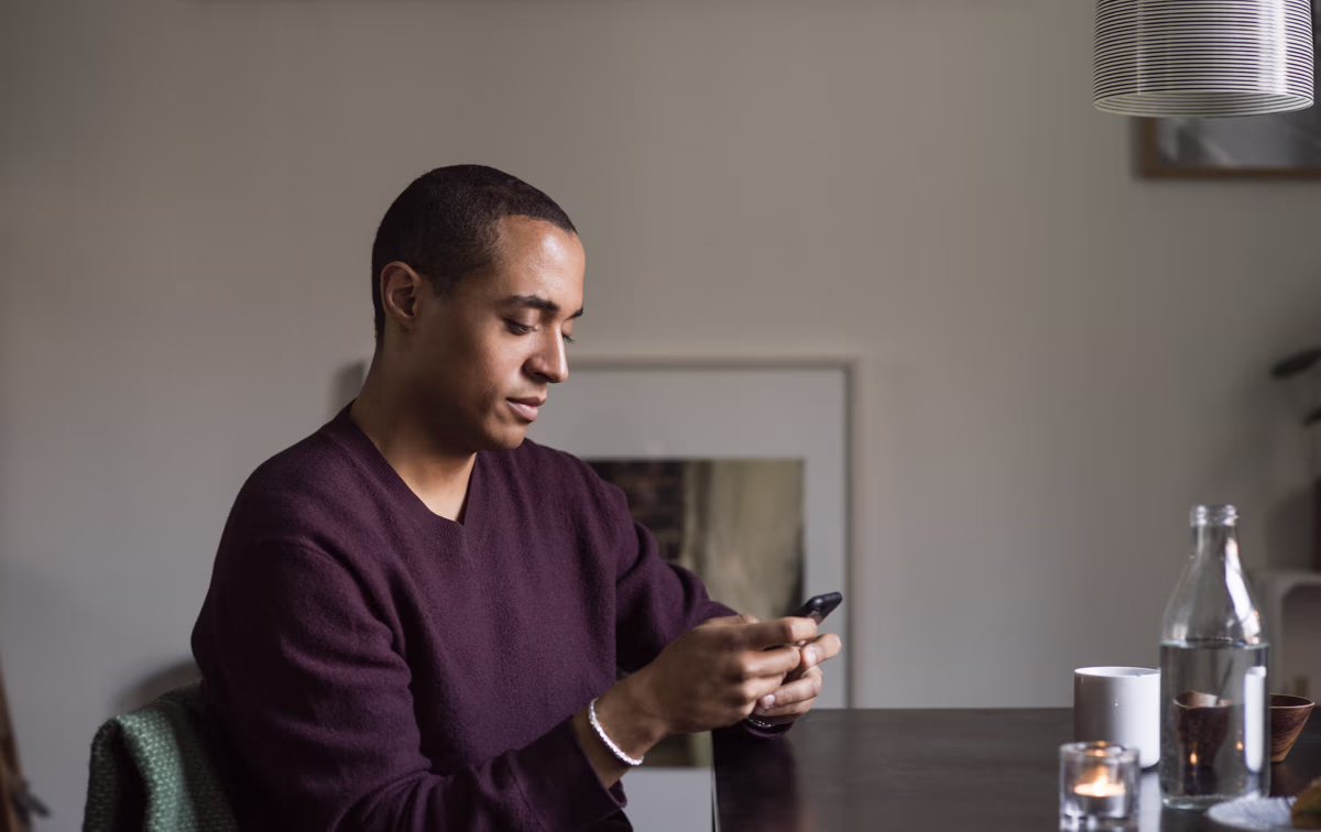 Mann sitter og ser på telefonen sin, illustrasjon av god kundeopplevelse.